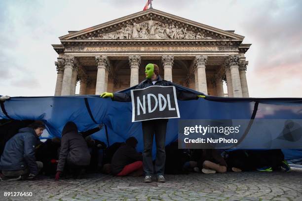 Masked protester wears a sign as climate activists put on a demonstration at the Place du Pantheon in Paris, France on December 12 the opening day of...