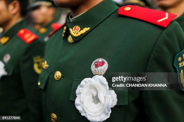 People's Liberation Army soldiers wears a flower as he participates in a memorial ceremony at the Nanjing Massacre Memorial Hall on the second annual...