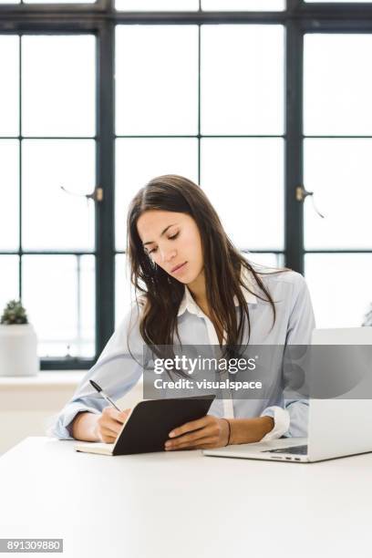 eurasian female business leader writing notes planning - eurasian ethnicity stock pictures, royalty-free photos & images