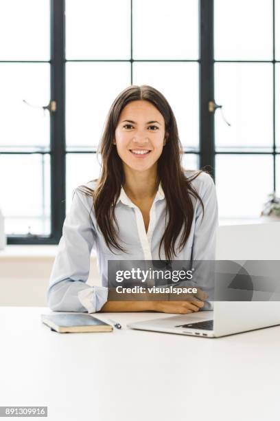 eurasische weibliche führungskraft sitzt an ihrem schreibtisch - eurasische herkunft stock-fotos und bilder