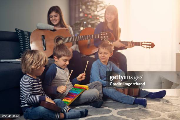 children practicing christmas carols near christmas tree - christmas orchestra stock pictures, royalty-free photos & images