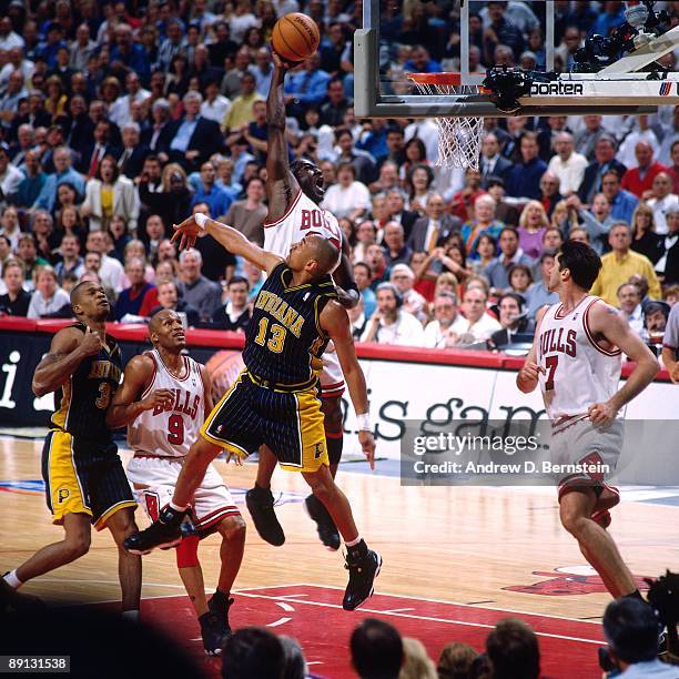 Michael Jordan of the Chicago Bulls dunks over Mark Jackson of the Indiana Pacers in Game Five of the Eastern Conference Finals during the 1998 NBA...
