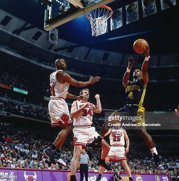 Travis Best of the Indiana Pacers shoots a layup against Scott Burrell and Bill Wennington of the Chicago Bulls in Game Five of the Eastern...