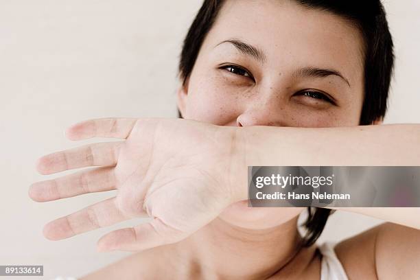 close-up of a woman covering her mouth - sheepish smile stock pictures, royalty-free photos & images