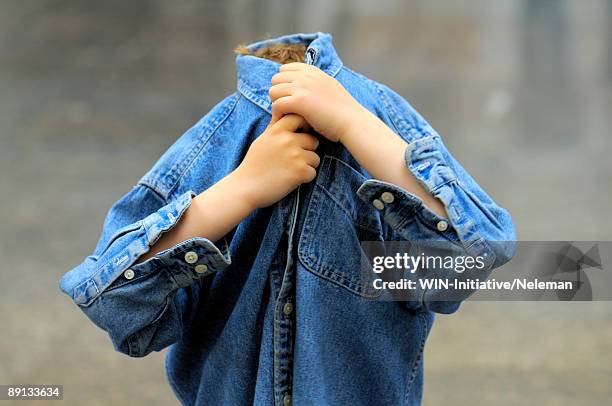 close-up of a boy covering his face with his shirt, kiev, ukraine - verlegen stockfoto's en -beelden