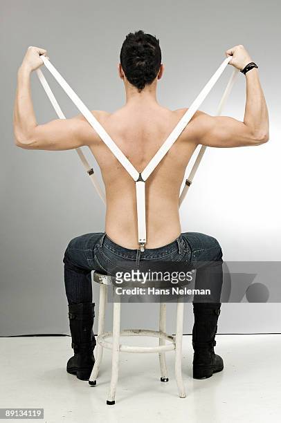 rear view of a man sitting on a stool and pulling suspenders - suspenders 個照片及圖片檔