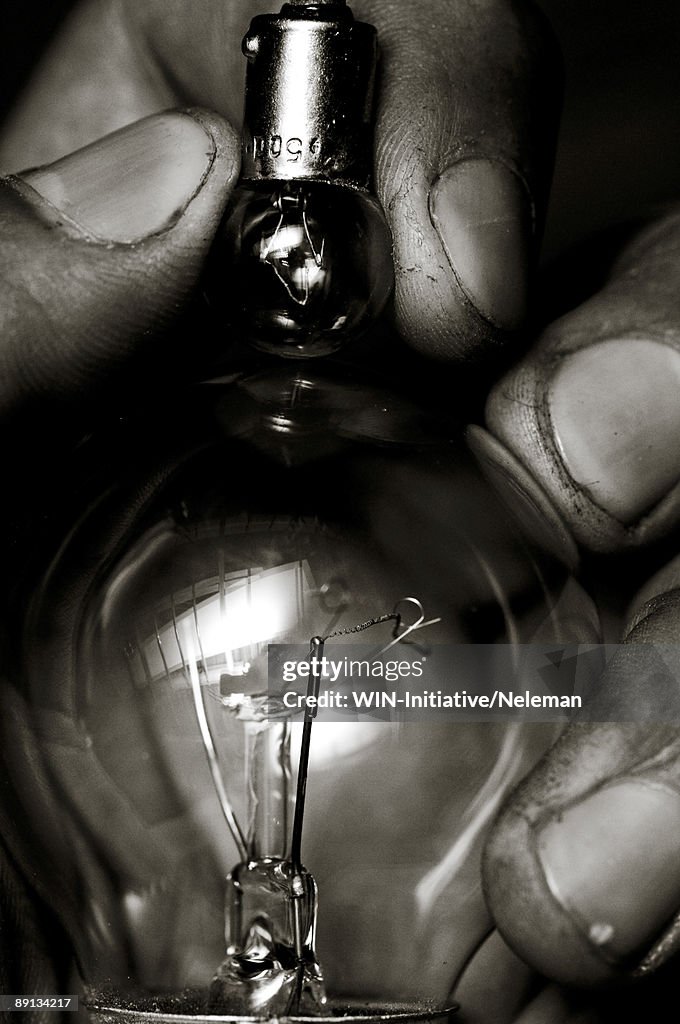 Close-up of a person's fingers holding light bulbs
