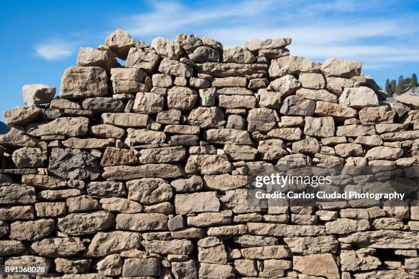 collapsed dry stone wall against blue sky - muro di pietra foto e immagini stock