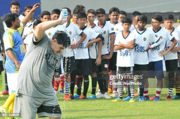 Argentine footballer Diego Maradona gestures as students looks on during a football workshop in Barasat, around 38 Km north of Kolkata on December...