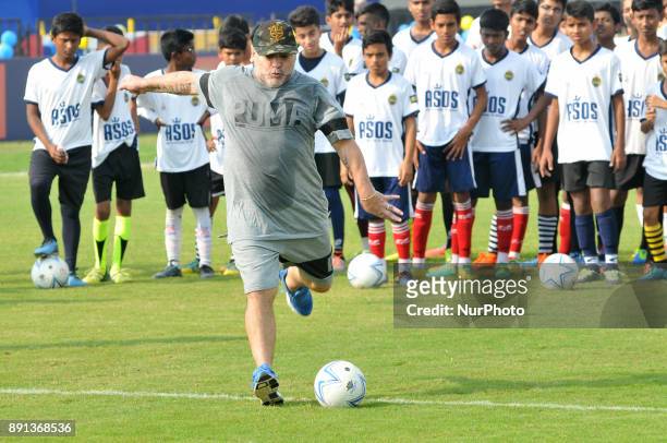 Argentina's soccer legend Diego Maradona kicks a football, gestures during a football workshop with school students in Barasat, around 38 Km north of...