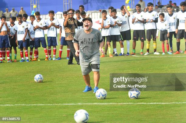 Argentina's soccer legend Diego Maradona kicks a football, gestures during a football workshop with school students in Barasat, around 38 Km north of...