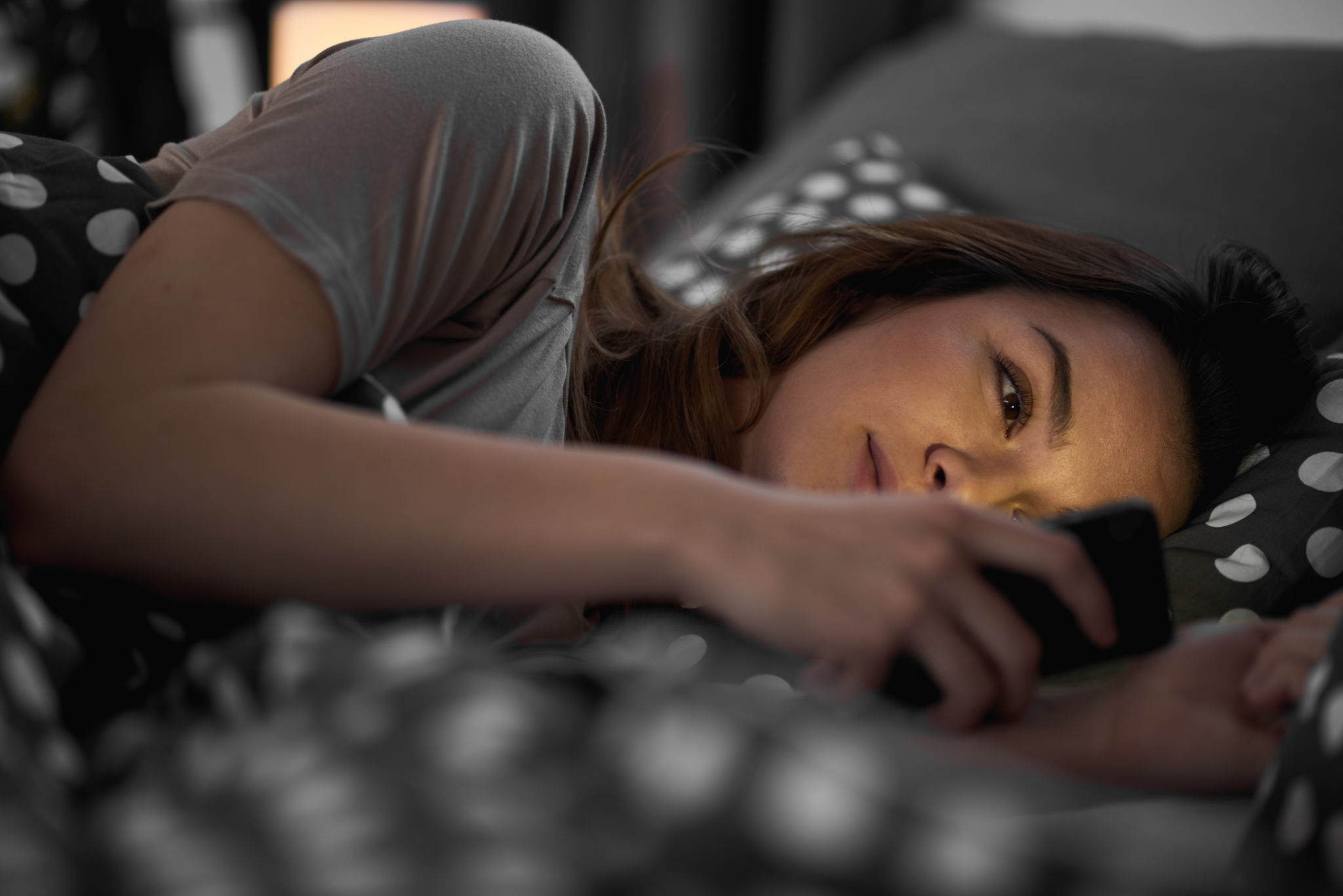Girl using smart phone and lying down in bed Girl using smart phone and lying down in bed