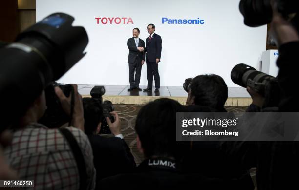 Akio Toyoda, president of Toyota Motor Corp., left, shakes hands with Kazuhiro Tsuga, president of Panasonic Corp., during a joint news conference in...