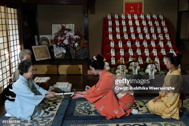 Maiko geisha girls bow as they receive a special fan from their traditional dance master Inoue Yachiyo , during an annual gratitude event for the...