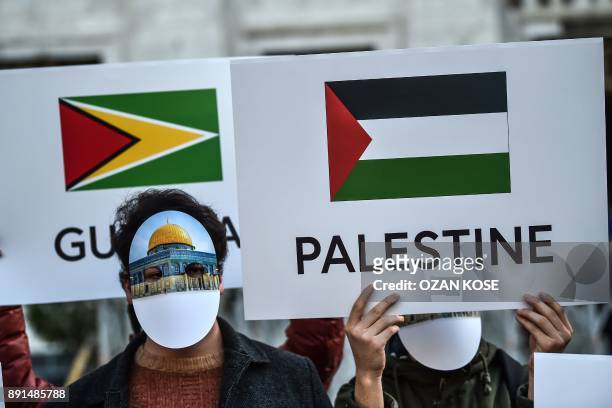Protesters wearing masks featuring Jerusalem's Dome of the Rock Mosque and holding a placard depicting the Palestinian flag, take part in a protest...