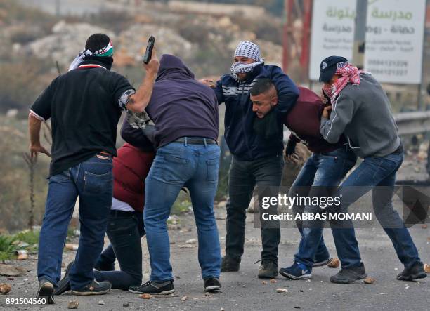Undercover Israeli police arrest Palestinian protestors during clashes following a demonstration in the West Bank city of Ramallah on December 13 as...