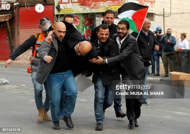 Palestinian protestors carry a man, wounded by a rubber bullet, during clashes following a demonstration in the occupied West Bank city of Bethlehem...