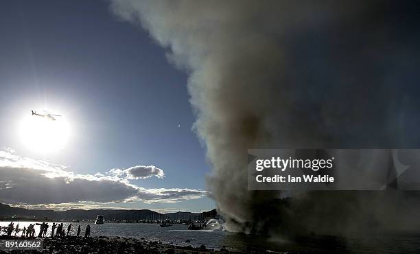 People watch as the remains of motorcruisers blaze at Sirsi Marina on July 22, 2009 on Pittwater at Newport on Sydney's Northern Beaches, Australia....