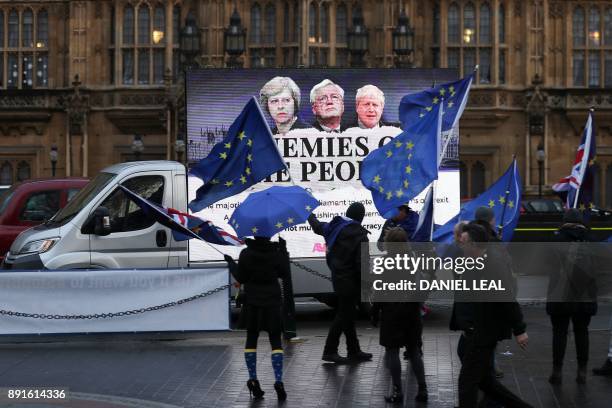 Pro-EU anti-Brexit demonstrators wave EU and Union Flags as a billboard depicting Britain's Prime Minister Theresa May, Britain's Secretary of State...