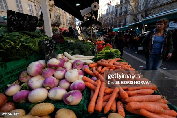 Customers choose fruit and vegetables as they do their shopping on stalls at Noailles Market in Marseille on December 13, 2017. / AFP PHOTO / BORIS...