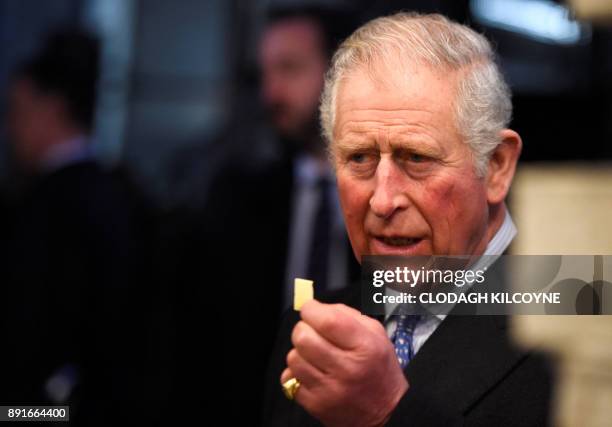 Britain's Prince Charles, Prince of Wales holds up a piece of cheese during a visit to Borough Market with Britain's Camilla, Duchess of Cornwall in...