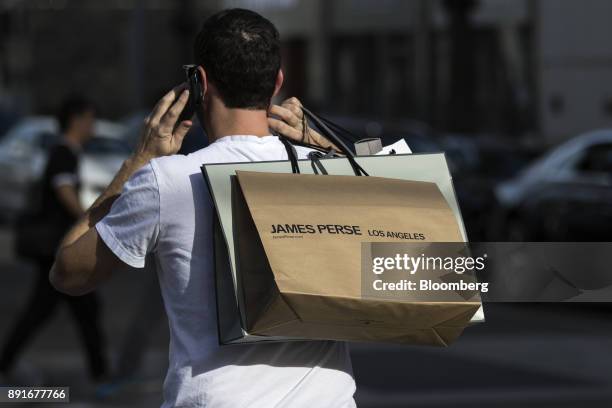 Shopper carries a James Perse Enterprises Inc. Bag while speaking on a mobile device on Rodeo Drive in Beverly Hills, California, U.S., on Saturday,...