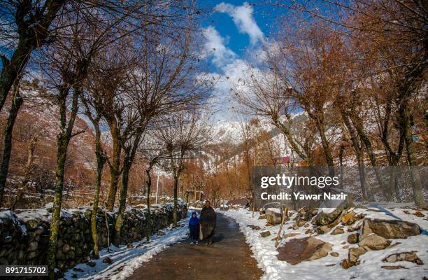 Kashmiri man walks with his daughter on a snow cleared road after seasons first snowfall on December 13, 2017In the outskirts of Srinagar, the summer...