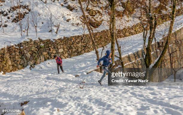 Kashmiri children play on snow after the seasons first snowfall on December 13, 2017 In the outskirts of Srinagar, the summer capital of Indian...