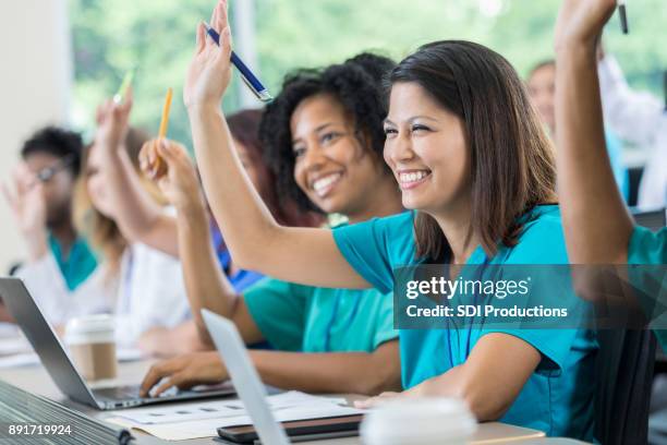 medizinstudenten heben die hände während des unterrichts - asian student classroom stock-fotos und bilder