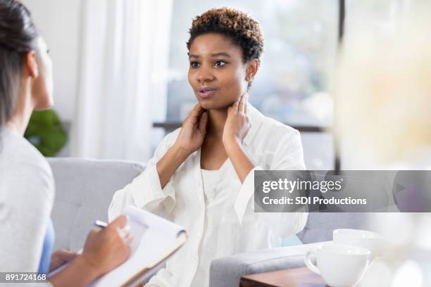 female patient describes symptoms to doctor - throat exam stock pictures, royalty-free photos & images