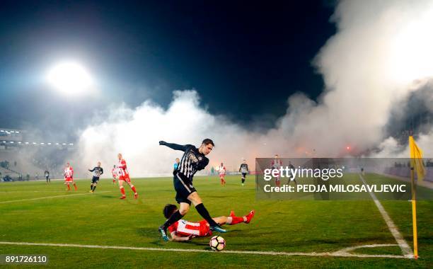 Partizan's Marko Jevtovic vies with Crvena Zvezda's Filip Stojkovic as smoke rise from the stands during the Serbian Superleague derby football match...