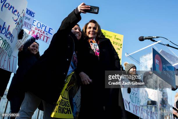 House Minority Leader Nancy Pelosi takes a photo with a supporter during a rally against the Republican tax plan on December 13, 2017 in Washington,...