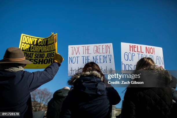 Demonstrators hold signs during a rally against the Republican tax plan on December 13, 2017 in Washington, DC.