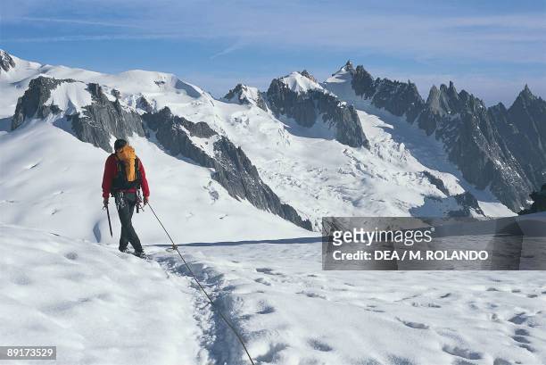 Rear view of a man walking on a polar landscape with rock formations in the background, Aiguille du Midi, Giant Glacier, Mt Blanc, Rhone-Alpes, France