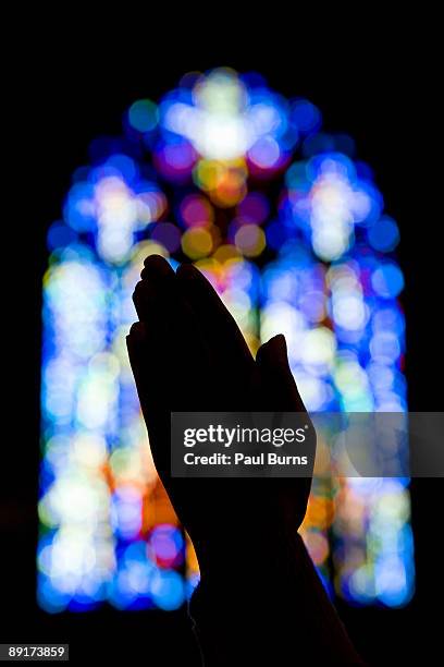 hands praying in church with stained glass - african american church stock pictures, royalty-free photos & images