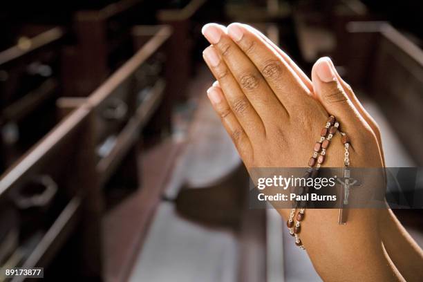 hands praying in church with rosary - gebetskette stock-fotos und bilder