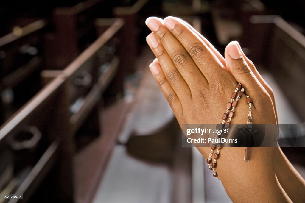 Hands Praying in Church With Rosary