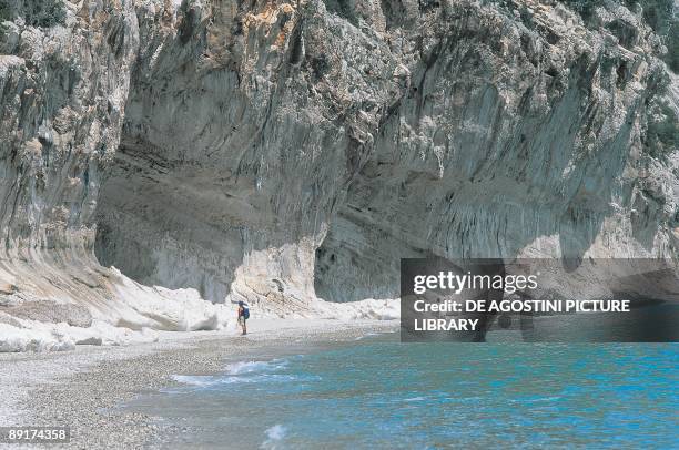 Three tourists standing on the beach, Cala Luna, Gennargentu National Park, Gulf Of Orosei, Sardinia, Italy