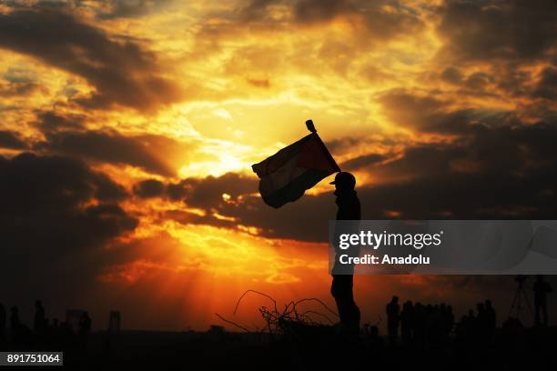 Palestinian's silhoutte is seen as he holds a Palestinian flag during a protest against U.S. President Donald Trump's announcement to recognize...