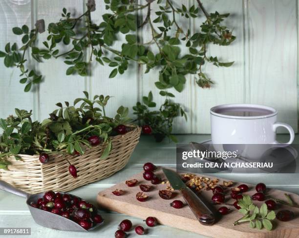 Close-up of dried wild rose fruits on a cutting board with a cup of rosehip juice