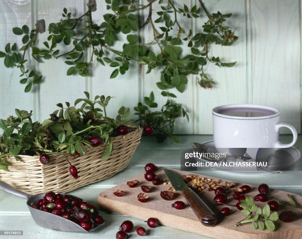 Close-up of dried wild rose fruits on a cutting board with a cup of rosehip juice