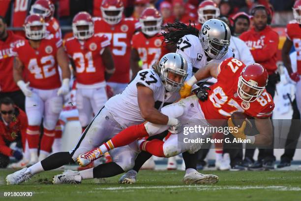 Defensive end James Cowser and free safety Reggie Nelson of the Oakland Raiders tackle tight end Travis Kelce of the Kansas City Chiefs during the...