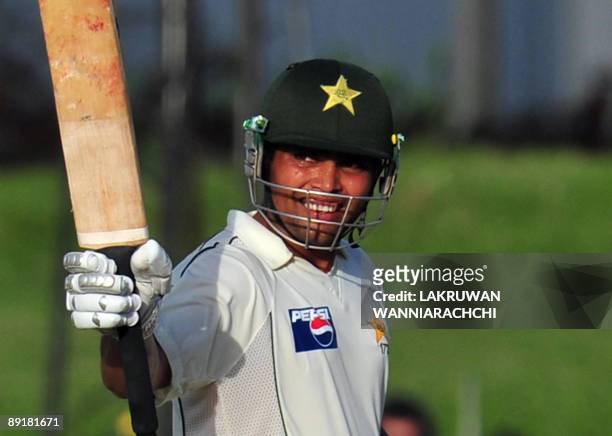 Pakistani cricketer Kamran Akmal raises his bat to the crowd after scoring a half-century during the third and final Test match between Sri Lanka and...