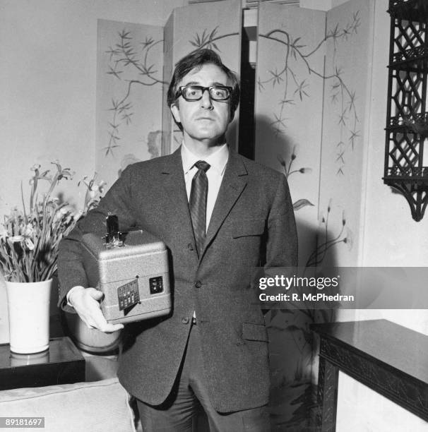 British actor and comedian Peter Sellers carrying a miniature fruit machine, an unusual Christmas present, 30th December 1965.