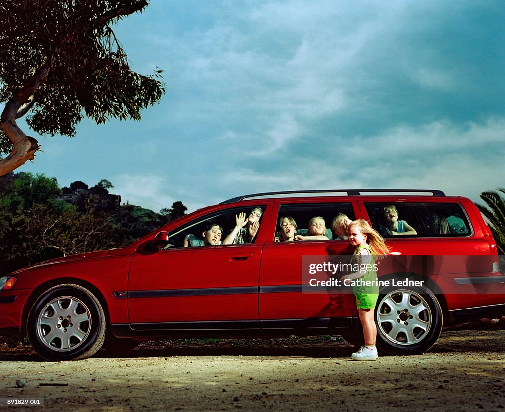 Children (5-10) making faces inside car windows, girl locked outside