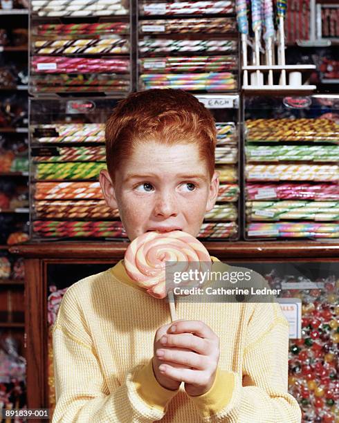 boy (8-10) eating lollipop in candy store - like a child in a sweet shop stock pictures, royalty-free photos & images