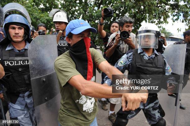 Supporter of ousted Honduran President Manuel Zelaya stands in front of soldiers in riot gear and police during a clash between marchs of supporters...