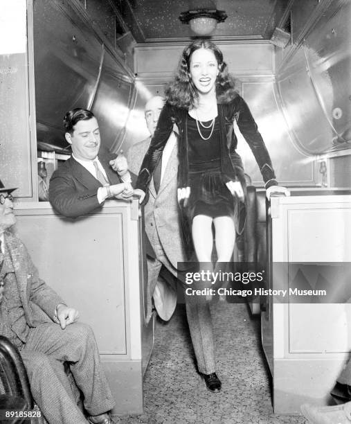 Informal full-length portrait of actress Lupe Velez bracing her hands on two low counters and holding her feet in the air in a passenger train car...