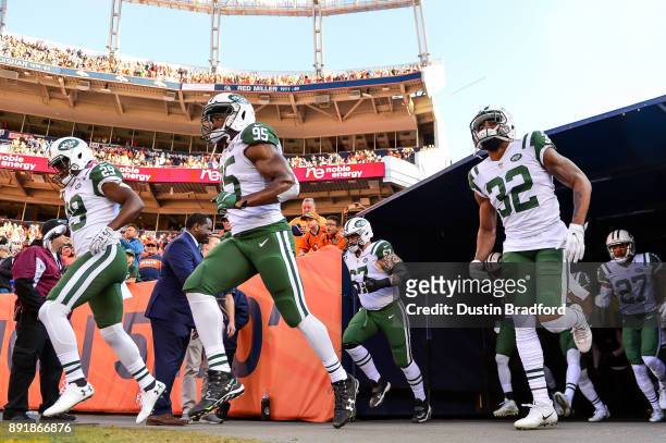 New York Jets players, including Bilal Powell, Josh Martin, and Juston Burris run onto the field before a game against the Denver Broncos at Sports...
