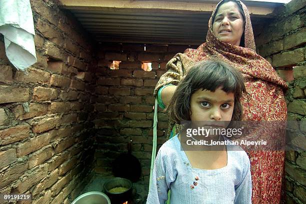Suni is standing near her mother in front of their makeshift kitchen made out of bricks in front of their tent, June 25 in Pakistan.
